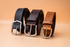 Three leather belts in black, brown, and tan on a beige background